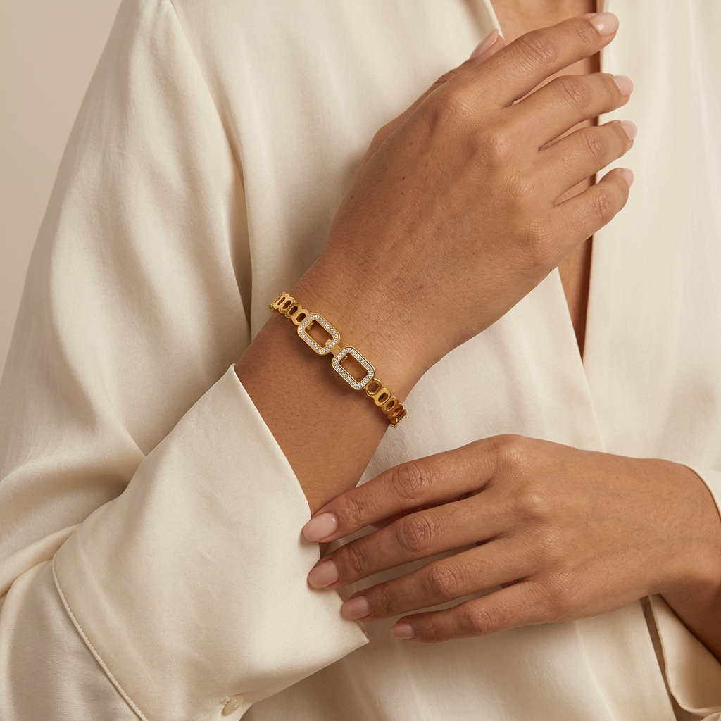 Frame gold-plated bangle worn near a cream blouse